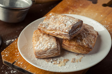 Few puff pastries in a white plate on a wooden table