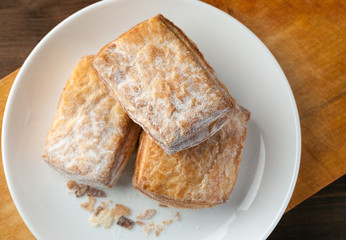 bakery in a white ceramic plate on a wooden board, top view
