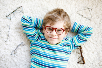 Close-up portrait of little blond kid boy with brown eyeglasses