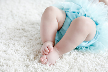 Close-up of legs and feet of baby girl on white background wearing turquoise tutu skirt. © Irina Schmidt