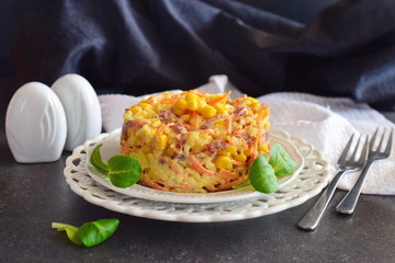 Salad with smoked sausage, corn, cheese, fresh carrot, egg, garlic and yogurt on a white plate on a abstract background