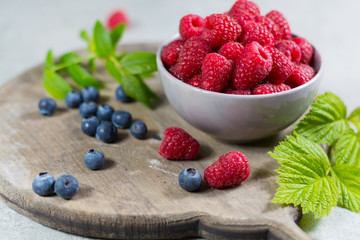 Fresh organic fruit - ripe raspberry with leaves on wood background