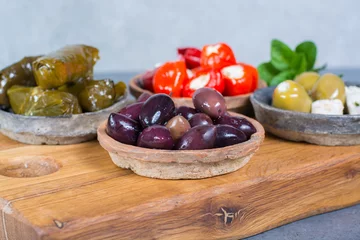 Foto op Plexiglas Mediterranean appetizer antipasti tapas bowls with green and calamata olives, feta cheese, stuffed pepper, herbs on wooden plank © barmalini