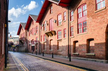 Fototapeta na wymiar Narrow Cobbled Street Lined with Renovated Old Warehouses. Leeds, UK