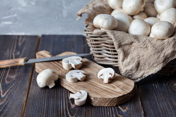 Mushrooms champignons in a basket on a neutral background