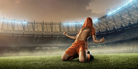 Obraz na płótnie Canvas soccer player in red uniform celebrates a goal on a soccer field