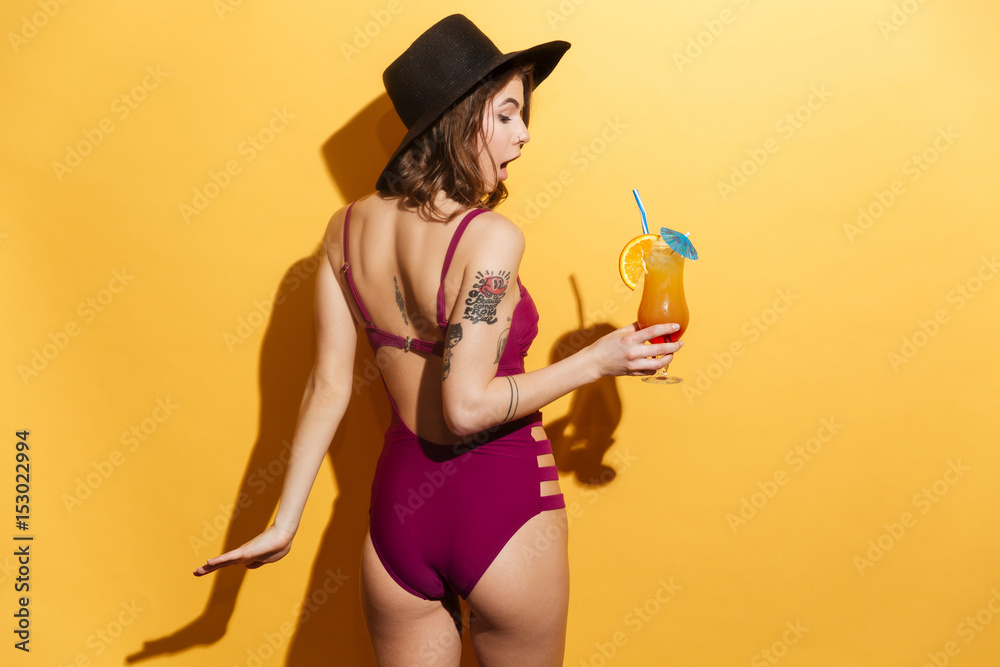 Sticker young girl in swimsuit holding fruit cocktail and looking away