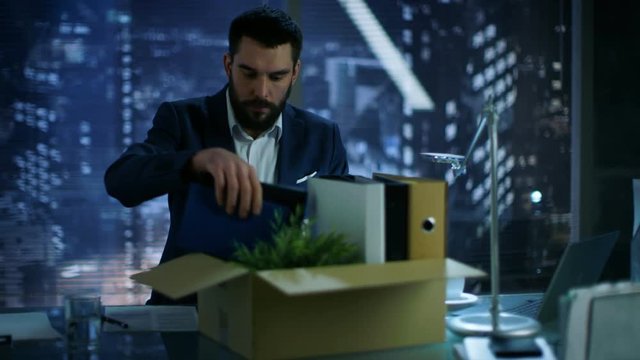Bankrupt Businessman Collects His Stuff in a Cardboard Box and Prepares to Leave His Company. In Background Big City Window View.Shot on RED EPIC-W 8K Helium Cinema Camera.