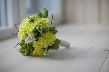 Beauty colored floral bouquet for romantic lovers on wooden board. Wedding gift for bridal. Mix flowers. A symmetrical round bouquet of yellow flowers, greenery and branches is on a wooden surface and