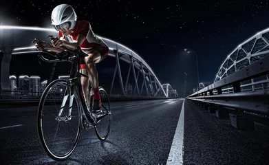 Foto op Aluminium Sport achtergronden. Atletische vrouw fietsen racefiets in de avond. Dramatisch uitzicht op de nachtstad. © vitaliy_melnik