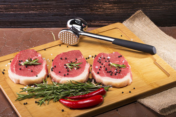 Meat for cooking steak, on a wooden background.