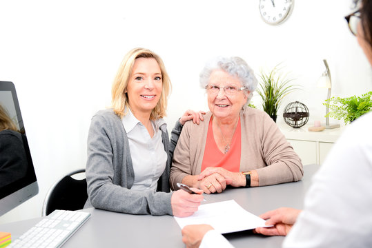 elderly senior woman with daughter signature legacy heritage testament document in a lawyer notary office