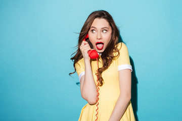 Attractive young girl in dress talking on retro telephone tube