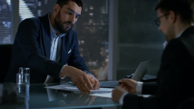Late at Night Businessman Businessman Has Conversation with Important Client, They Come to an Agreement, Both Sign Contract. In the Background Big City Window View. Shot on RED EPIC-W 8K Helium Camera