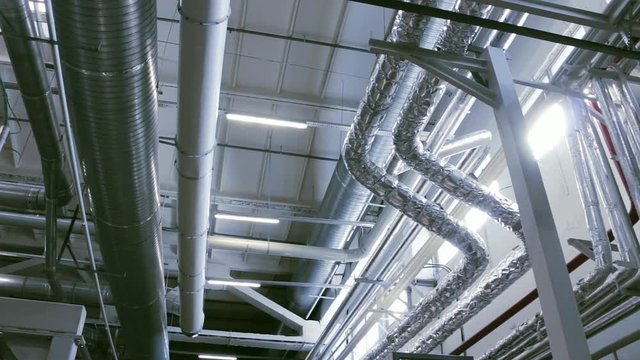 Slow pan of industrial conditioning, heating and ventilation pipes located indoors.