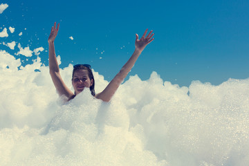 Happy young woman dancing on beach foam party