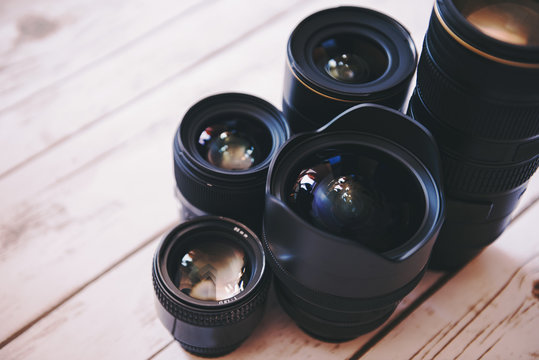 Professional camera lenses on a wood background.