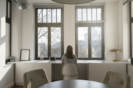 Woman in front of panorama window at home with tablet