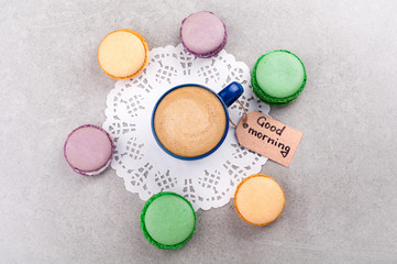 Breakfast concept. Coffee cup and macaroon or macaron, note good morning. Flat lay. Top view