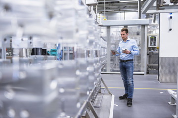 Man with tablet in factory shop floor examining products
