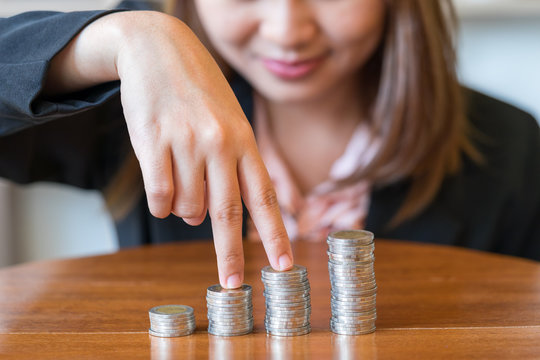 Close up smile business woman with savings coins on table - finance concept