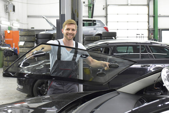 Car mechanic in a workshop changing car window