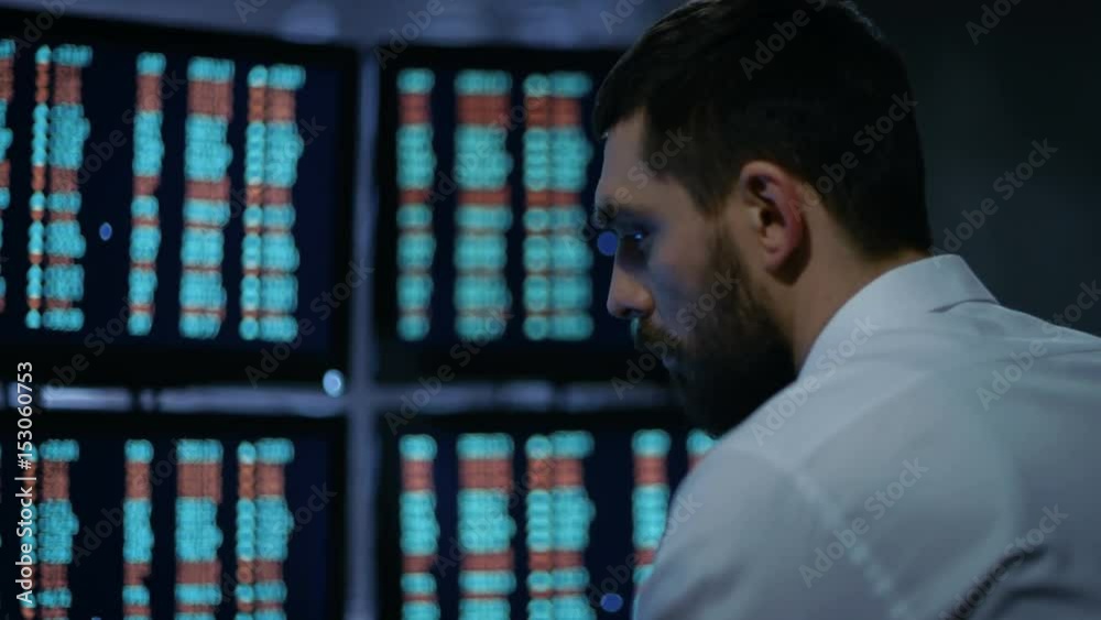 Poster Late at Night Trader Reads Numbers on His Multiple Displays with Stock Information on Them. In Background Big City Window View. Shot on RED EPIC-W 8K Helium Cinema Camera.