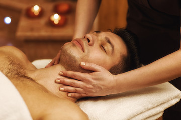 Fototapeta na wymiar Handsome young man enjoying massage at spa center