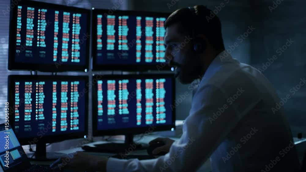 Poster Late at Night Trader Reads Numbers on His Multiple Displays with Stock Information on Them, He Also Consults Clients with Headset On. In Background Big City Window View. Shot on RED Cinema Camera 4K