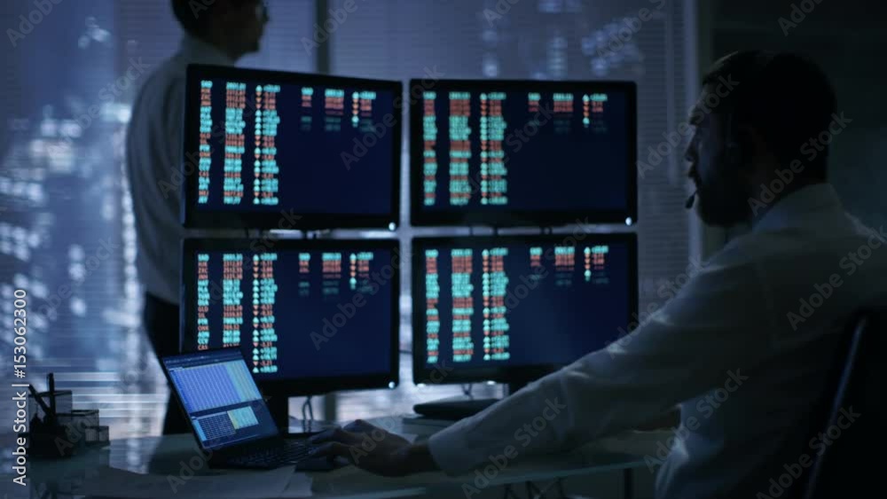 Poster late at night in trader's bureau. stockbroker reads numbers on his multiple displays with stock info