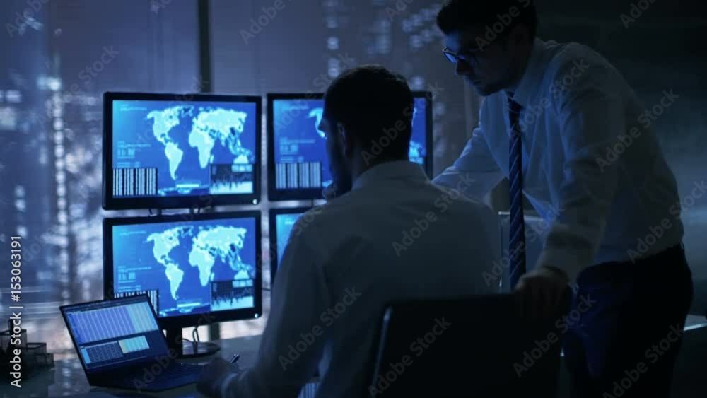 Poster Late at Night in Office Building Security Service Men Have Discussion while  Attentively Observing Monitors with Location Sensitive Information Shown on Them. Shot on RED EPIC-W 8K Helium Camera