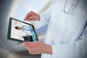 Composite image of doctor using digital tablet