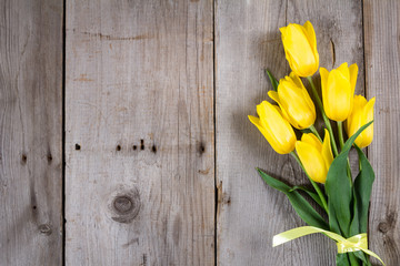 Bouquet of yellow tulips and gift box on grey wooden background