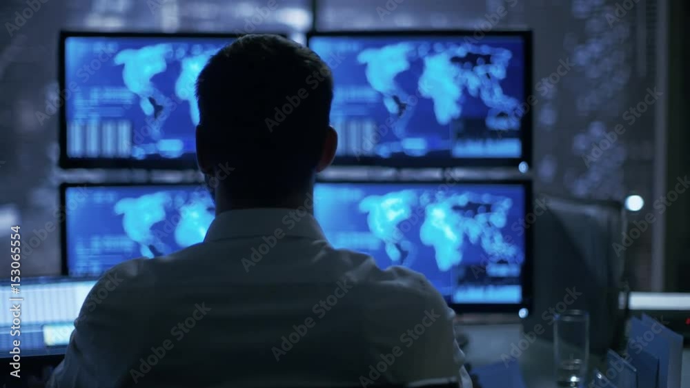 Poster Late at Night Security Operator Attentively Observes His Monitors with Location Sensitive Information Shown on Them.  Shot on RED EPIC-W 8K Helium Cinema Camera.