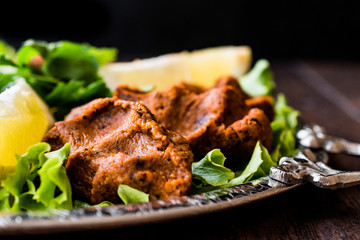 Turkish Food Cig Kofte with lemon, lettuce and parsley on silver tray.