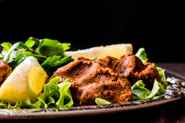 Turkish Food Cig Kofte with lemon, lettuce and parsley on silver tray.