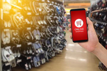 human hand hold smartphone, tablet, cell phone with shop cart online shopping on blurry footwear...