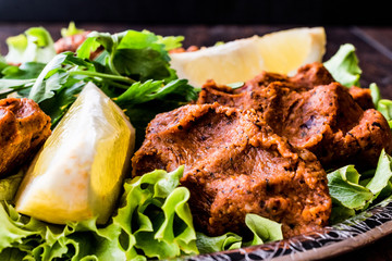 Turkish Food Cig Kofte with lemon, lettuce and parsley on silver tray.
