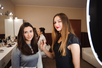 Make up artist doing professional make up of young woman. Beauty shcool.