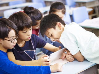 asian schoolchildren using digital tablet together