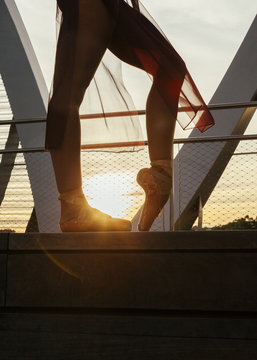 ballerina woman performing a pose with old classic shoes on a metal bridge