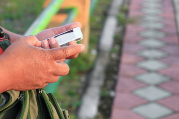 close up hand holding  using a cell phone in public park