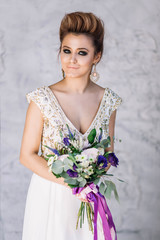 beautiful sexy girl bride blonde with tanned skin in a white dress with gold decorations with wedding bouquet makeup and hair in the Studio looking at the camera with smiling closeup white background