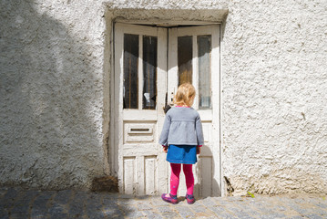 Fototapeta na wymiar The little girl was staring at the old door in the street