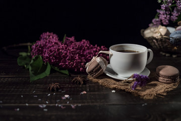 Coffee and cream macaroons in an eastern vase and a linen napkin on a lilac background