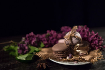 Coffee and cream macarons on a white plate and a linen napkin on a background of lilac
