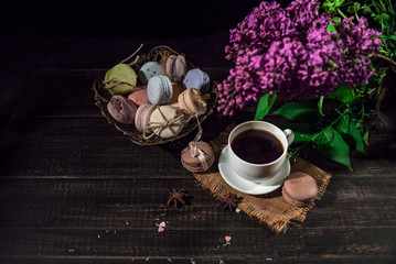 Coffee and cream macaroons in an eastern vase and a linen napkin on a lilac background