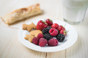 Rustic healthy breakfast with blueberry, raspberry, crackers, small loaf and milk in a glass on a wooden table. Healthy breakfast with vital vitamins.