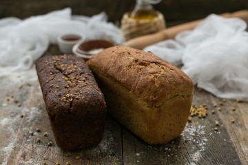 Close up view of fresh brown crispy loaf of bread lying on the wooden table sprinkled with flour.
