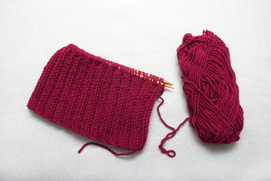 The process of knitting a scarf-snud on circular wooden knitting needles from red wool, warm winter asseksuar